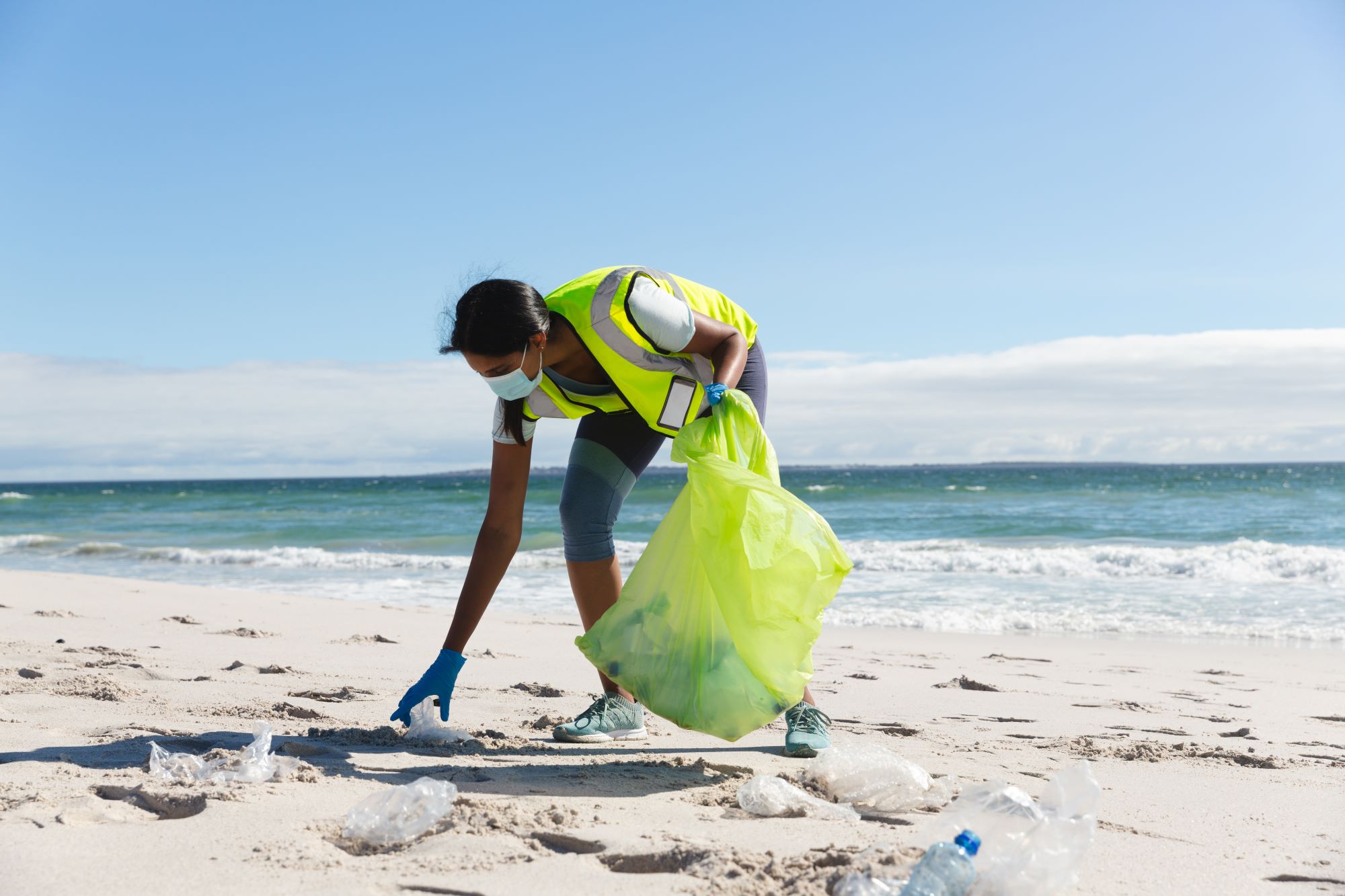 “A Group Of Volunteers Picking Up Trash On The Beach”